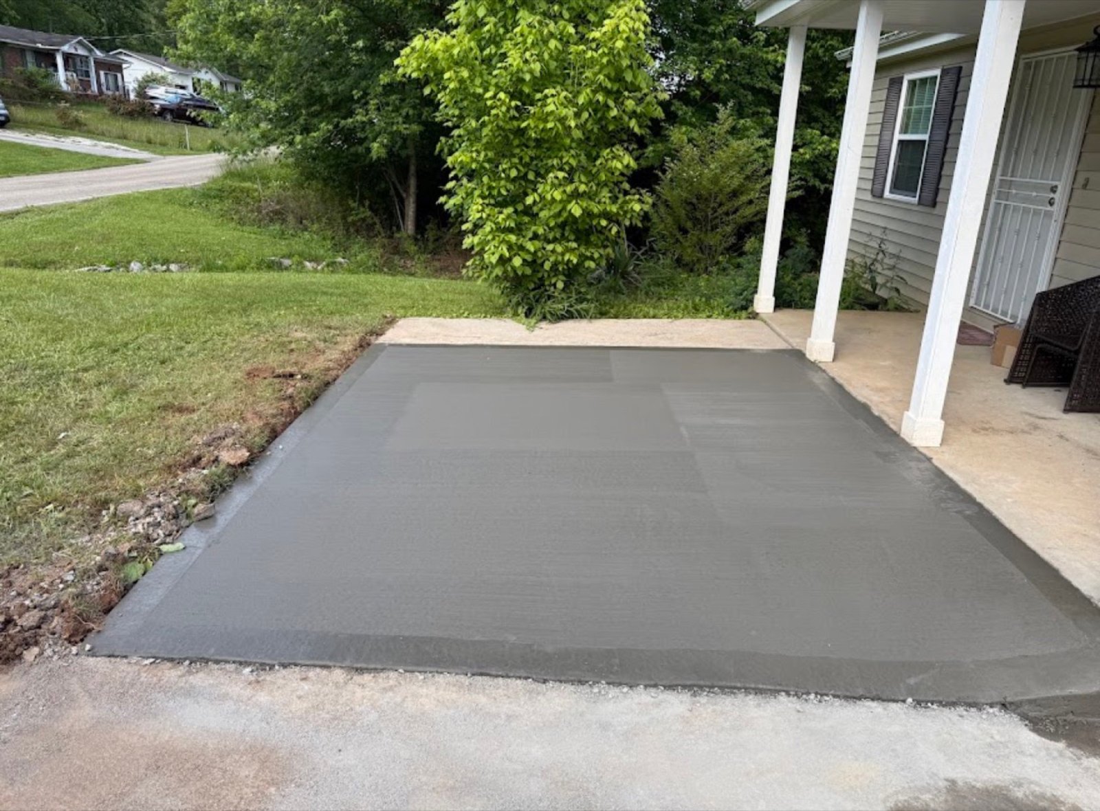 Freshly poured concrete patio slab beside a home