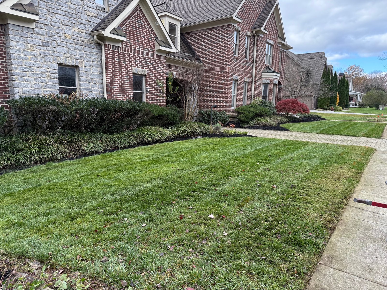 Manicured front lawn with mow stripes and freshly mulched shrub beds at an upscale home